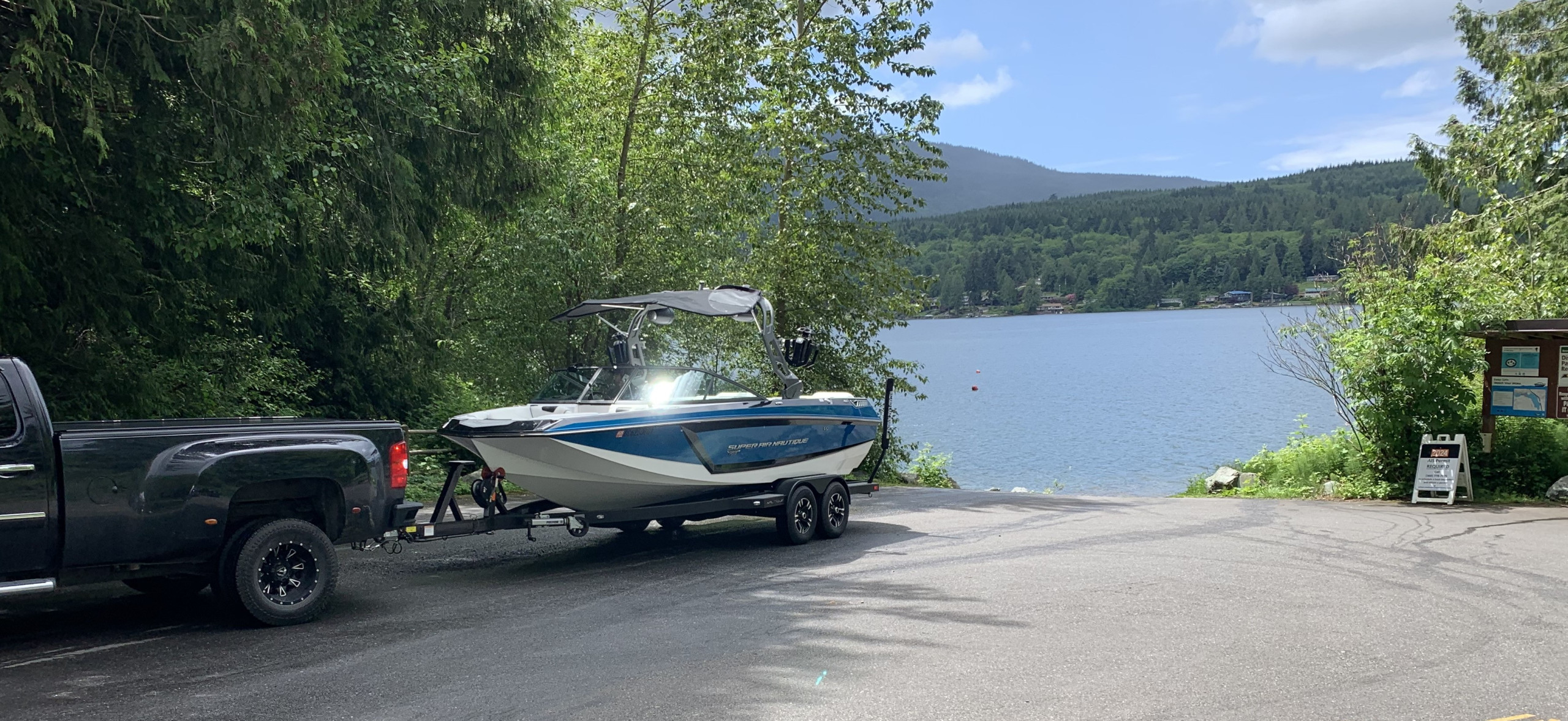 Wakeboard boat attached to a trailer on a boat launch